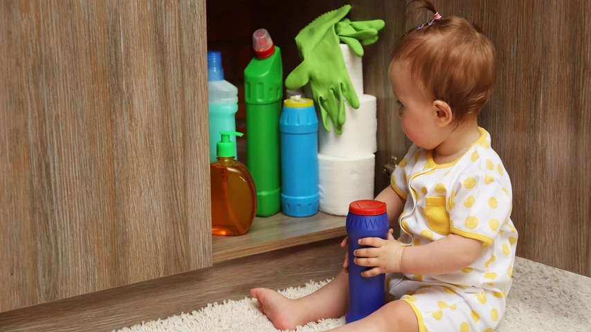 Little girl playing with detergents in kitchen